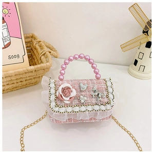 Detail view of pink tweed kids crossbody bag with pearls and floral bow accents