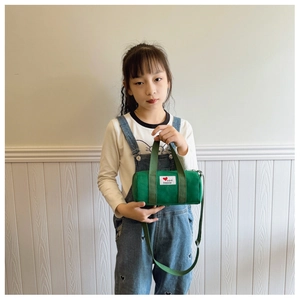 Detail view of green canvas bucket bag for kids with fashion patch and shoulder strap