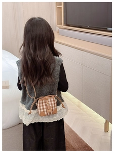 Detail view of a brown plaid mini crossbody bag for kids with leather trim and magnetic closure