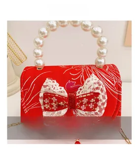 Detail of red satin girls handbag with pearl handle, lace bow, and elegant tassel