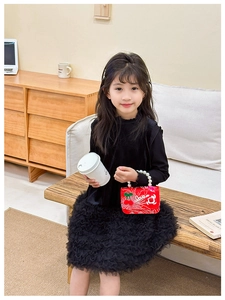 Detail of red cherry handbag with pearl handle and little girl's black mesh dress
