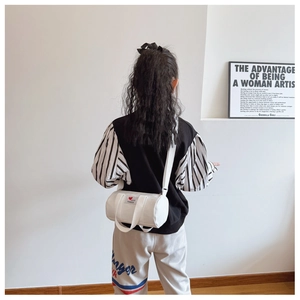Rear view of a child wearing a white canvas cylinder bucket bag with a red heart patch