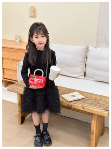 Detail of red cherry handbag with pearl handle paired with a black tutu dress