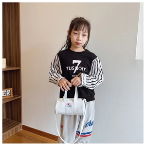Detailed close-up of a white canvas cylinder bag for kids with red heart patch