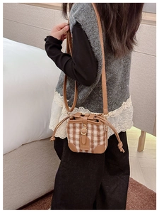 Detail of checkered plush kids bucket bag with brown faux leather trim and drawstring
