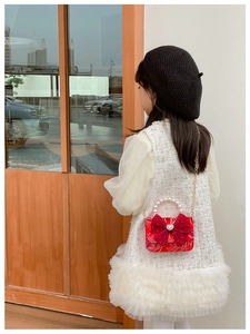 Detail of red New Year girl bag with large satin bow and white pearl handle