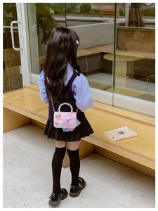 Pink child handbag with pearl handle and unicorn mesh detail shown in outdoor setting