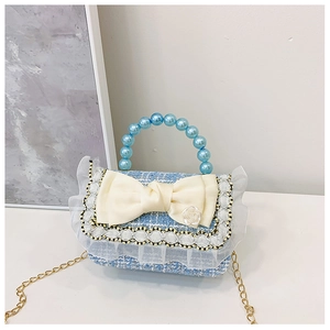 Detail of blue tweed mini bag featuring a large cream bow with rose and pearl handle
