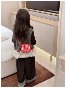 Detail view of red checkered crossbody bag for children with fashion label and drawstring