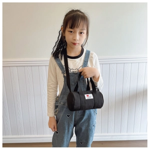 Close-up of kids black canvas bucket bag with heart patch and fashion lettering strap
