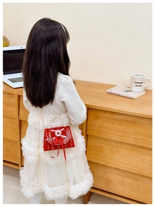 Detail of red girl's handbag with large bow, pearl handle, and soft plush charm