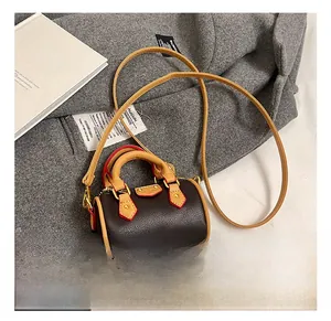 Détail d'un mini sac cylindre marron en cuir PU avec anses jaunes et finitions dorées