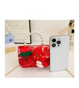 Size comparison of red girls' handbag with pearl handle and embroidered details