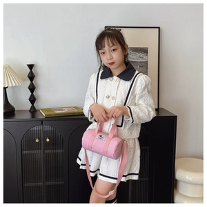 Pink cylinder canvas bucket bag for kids worn by a model in a cozy home setting