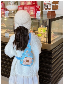 Detailed view of child wearing blue Capybara printed crossbody bag in a cozy bakery setting
