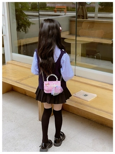 Detail of pink child's crossbody bag with pearl handle, mesh bow, and metal chain strap