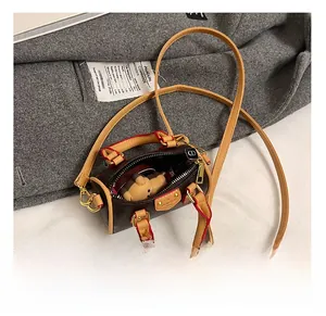 Vue détaillée du mini sac cylindrique montrant le rouge à lèvres et le charm intérieur
