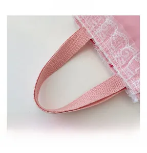 Detail shot of the pink girl's handbag with elegant white lace trim and sturdy handles