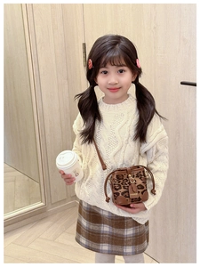 Close-up of leopard print kids bucket bag with brown leather trim and fashion label