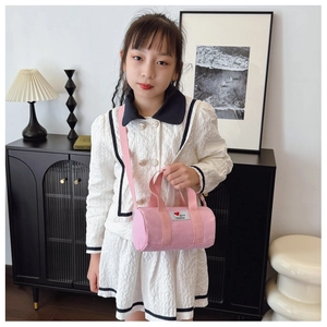 Close-up of a pink canvas bucket bag for kids with adjustable strap and heart patch detail