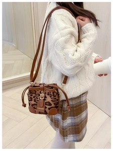 Detail of leopard print mini bucket bag with leather accents and gold-toned buckle