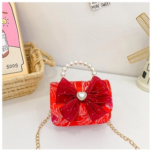 Detail of kids red velvet bow bag featuring heart pearl and beaded pearl handle