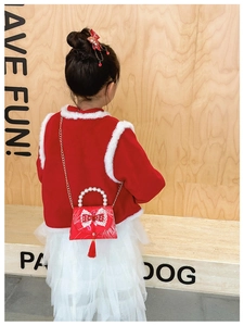 Detail of red festive girl's handbag with pearl handle, lace bow and tassels