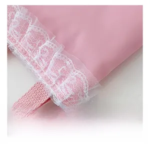 Close-up of pink twill fabric texture and delicate white lace trim on the girl's handbag