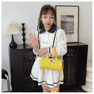 Close-up of a yellow canvas bucket bag for kids with fashion heart patch and shoulder strap