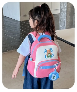 Detailed back view of pink and white bear backpack on a young girl model
