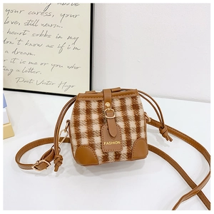 Detail of wool blend plaid bucket bag with brown leather trim and drawstring closure