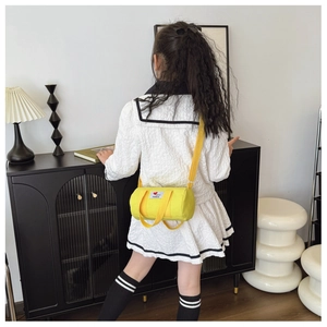 Detail of a bright yellow canvas bucket bag showing fashion patch and adjustable strap