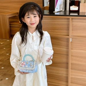 Blue tweed girls crossbody bag with pearl handle and floral lace details on a young model