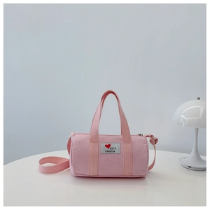 Close-up of pink canvas bucket bag featuring a stitched logo patch and heart detail
