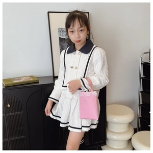 Detail of girls' white textured set featuring black contrast collar and pleated mini skirt