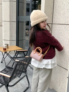 Mini borsa a cilindro rosa indossata da una piccola modella in un contesto street style