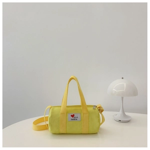 Detail of yellow canvas bucket bag with heart patch and adjustable shoulder strap