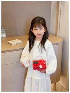 Detail of red sequin kids bag featuring a crochet cherry and pearl handle on child model