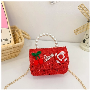 Detail of red sequined girl's handbag with pearl handle and cherry charms
