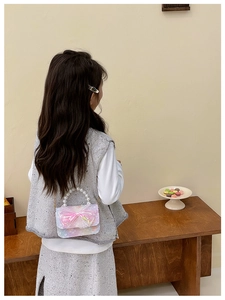 Detail of sweet girls crossbody bag with iridescent fabric and large lace bow decoration