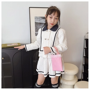 Detail of girls' white jacquard two-piece set featuring black trim and silver buttons