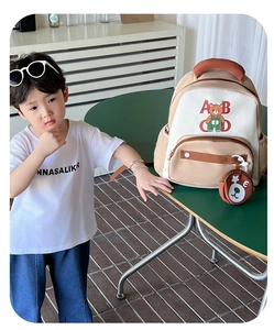 Detail of kids backpack with bear pattern, red letters, side mesh pocket and round charm