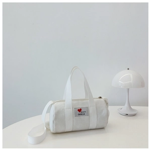 Detailed macro view of white canvas bucket bag with heart patch and dual carry straps