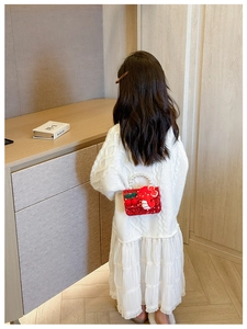 Girl wearing a red sequined handbag with pearl handle, dragon plush, and cherry charm