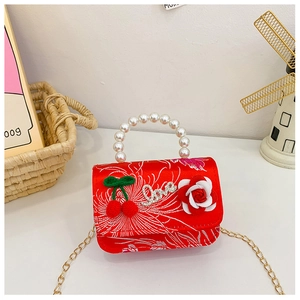 Detail of red floral child handbag with pearl handle and cherry decoration