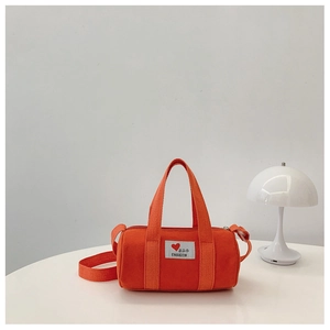 Detail of orange canvas bucket bag with heart patch and adjustable shoulder strap