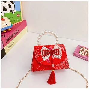 Macro shot of red satin kids purse with pearl handle, tassel, and floral cloud pattern