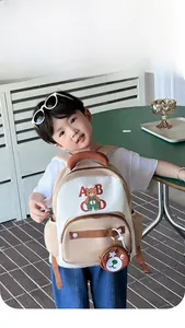 Kid back view wearing a cream and brown bear backpack with ABCD letters and bear charm
