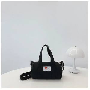 Detail of black canvas bucket bag featuring Bag Fashion patch on a white table