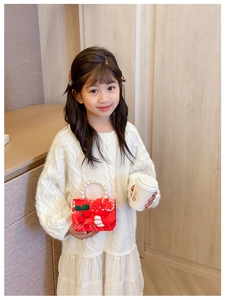 Detail of red festive girl's bag with pearl handle and knit cherry decoration